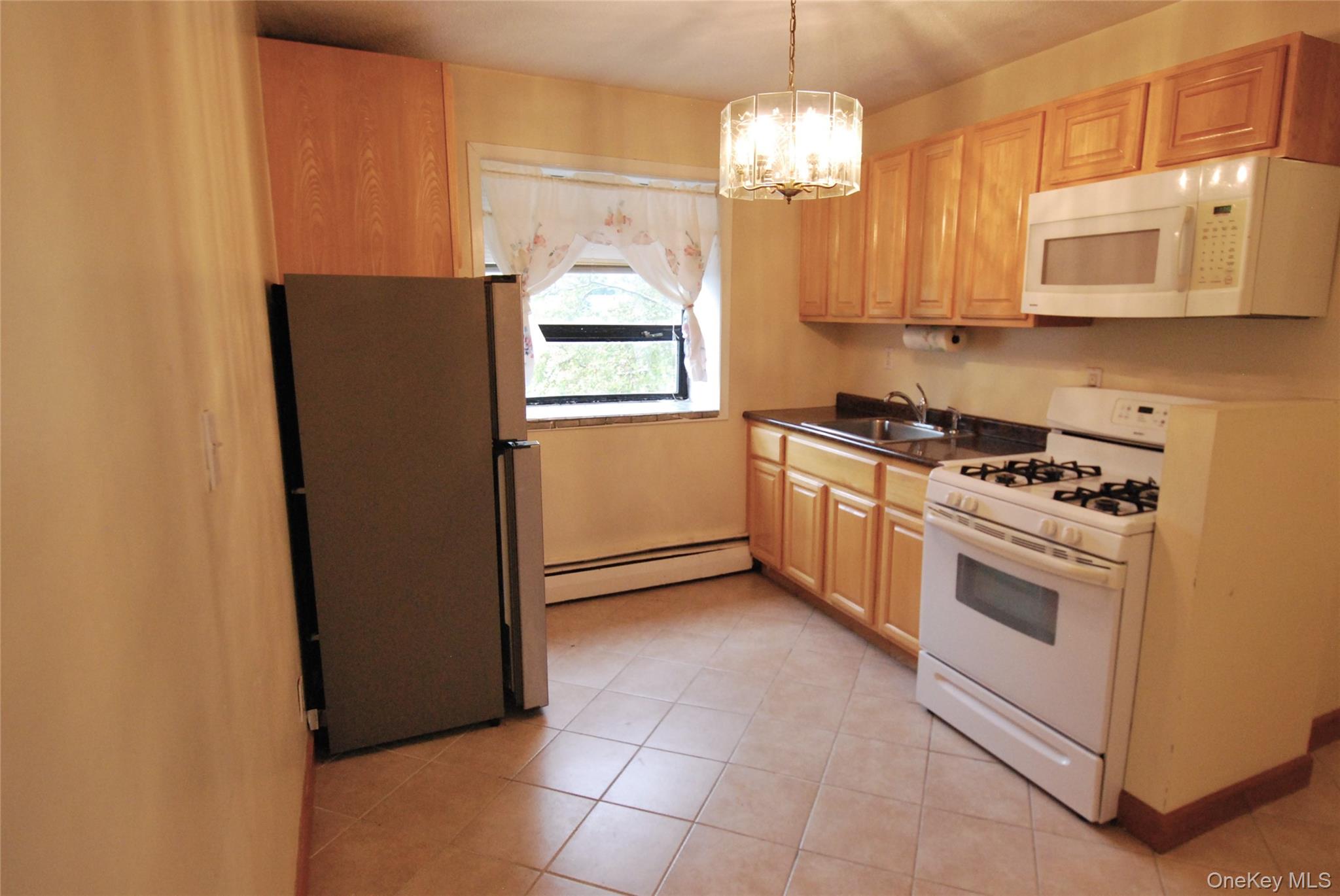 1523 Central Park Avenue, Unit 5F Yonkers, NY 10710 - Photo 6 of 20 a kitchen with stainless steel appliances granite countertop a refrigerator a stove a microwave oven with cabinets and wooden floor