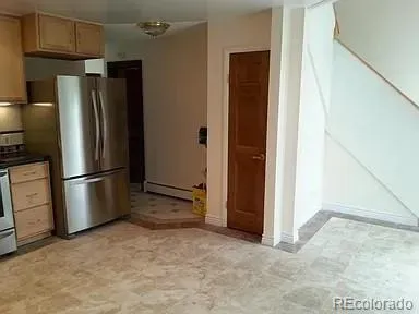 a view of a refrigerator in kitchen and an empty room