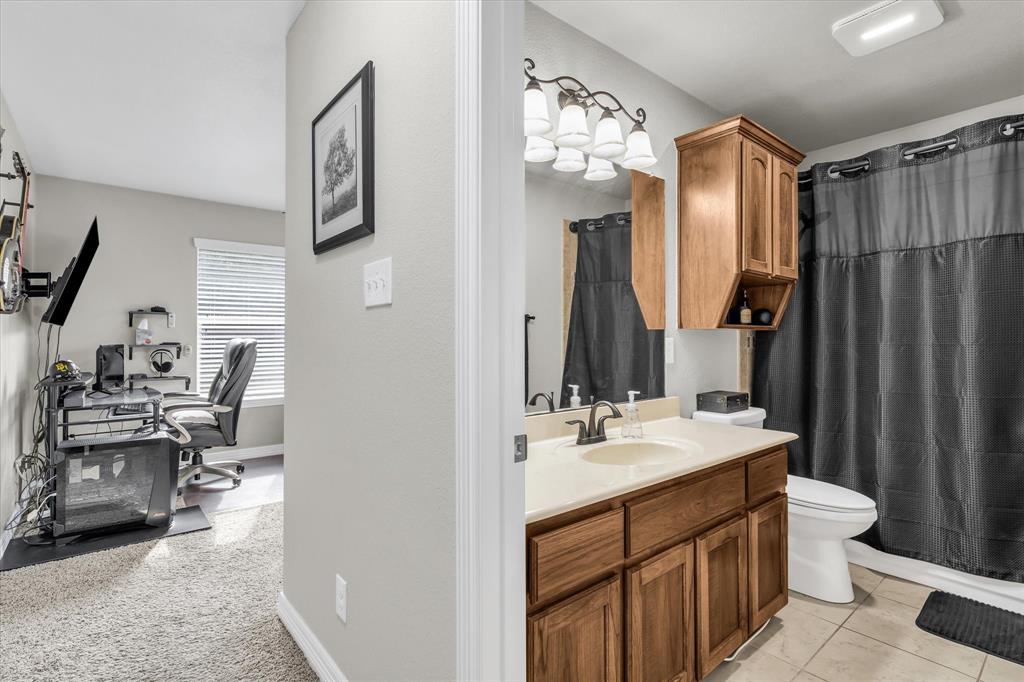910 Springdale Lane Lorena, TX 76655 - Photo 25 of 39 Bathroom vanity featuring a light-colored countertop, wood-finish cabinetry, and an ornate five-light fixture