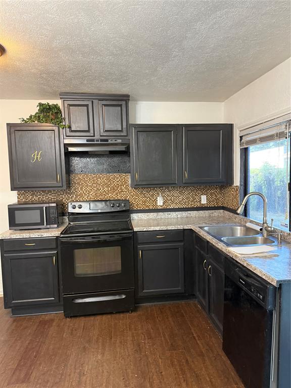 3801 Guthrie Road Garland, TX 75043 - Photo 2 of 24 Kitchen featuring dark wood-finish cabinetry, mosaic tile backsplash, wood-finish flooring, stainless steel double basin sink, and black appliances