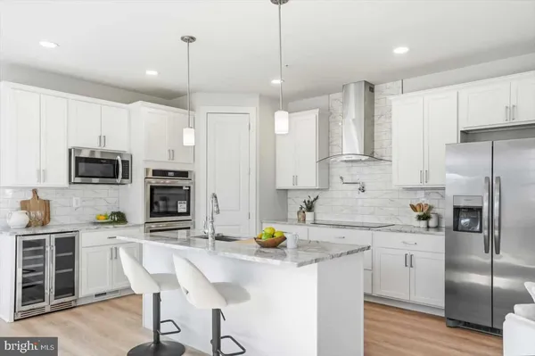 a kitchen with stainless steel appliances kitchen island granite countertop a refrigerator a stove microwave and white cabinets with wooden floor