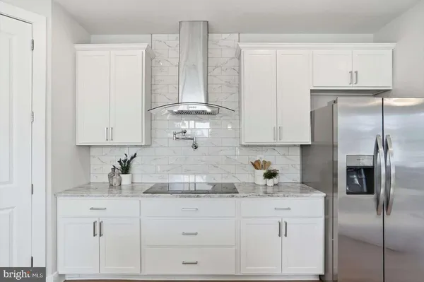 a kitchen with white cabinets and refrigerator