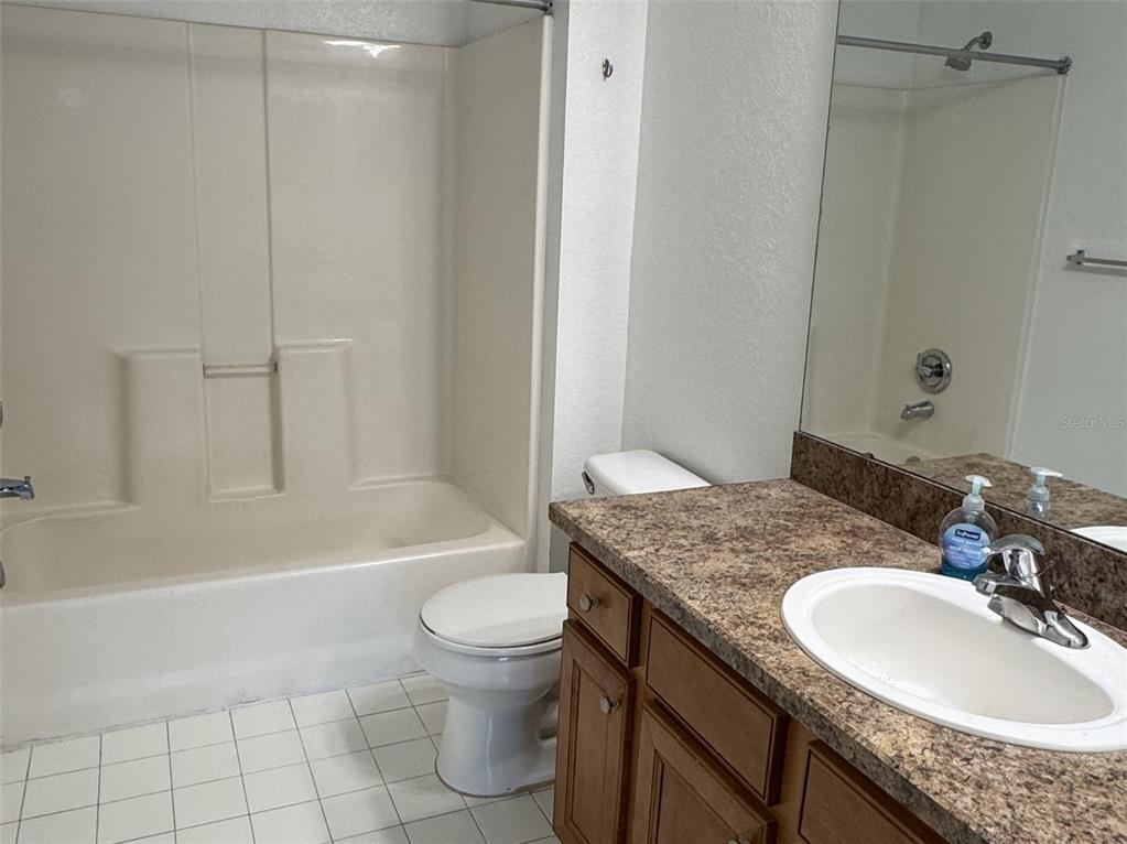 5483 Vineland Road, Unit 10201 Orlando, FL 32811 - Photo 18 of 35 a bathroom with a granite countertop sink a toilet a mirror and bathtub