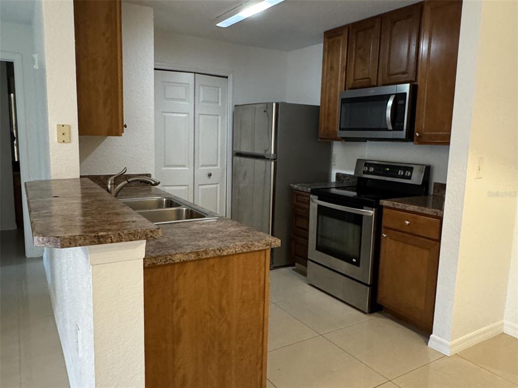 5483 Vineland Road, Unit 10201 Orlando, FL 32811 - Photo 7 of 35 a kitchen with granite countertop wooden cabinets and stainless steel appliances