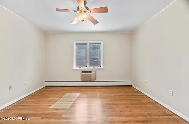 an empty room with wooden floor chandelier fan and windows