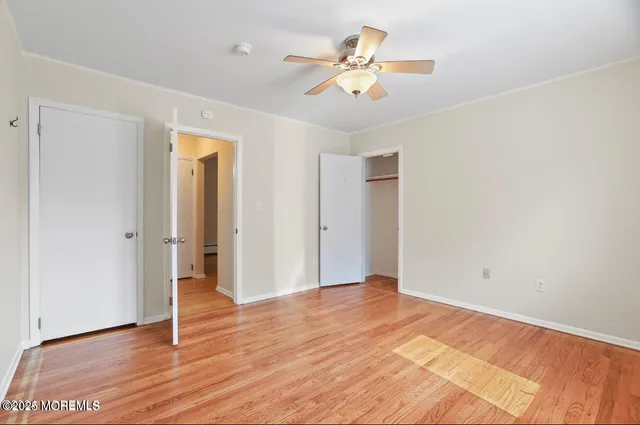 an empty room with wooden floor and ceiling fan