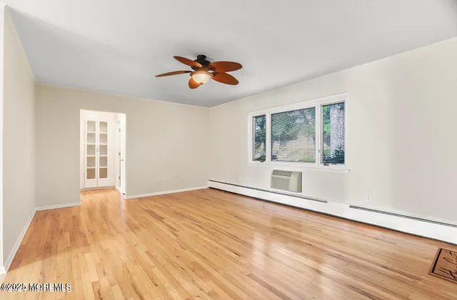 a view of an empty room with a window and wooden floor