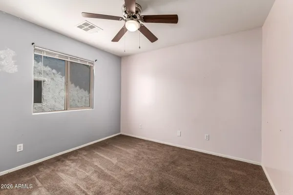 an empty room with a window and a fan