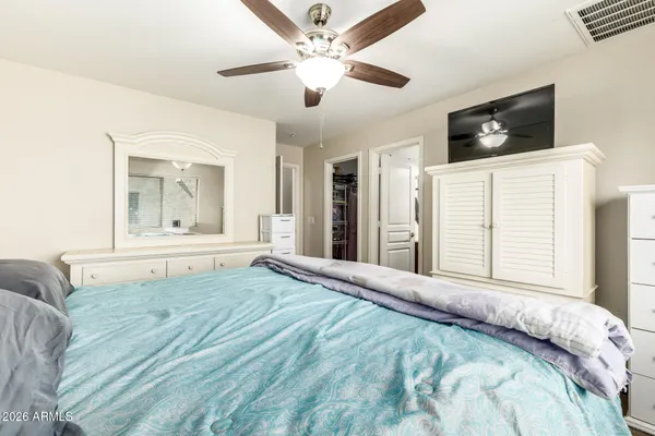 a large bedroom with a large bed a flat tv screen and dresser