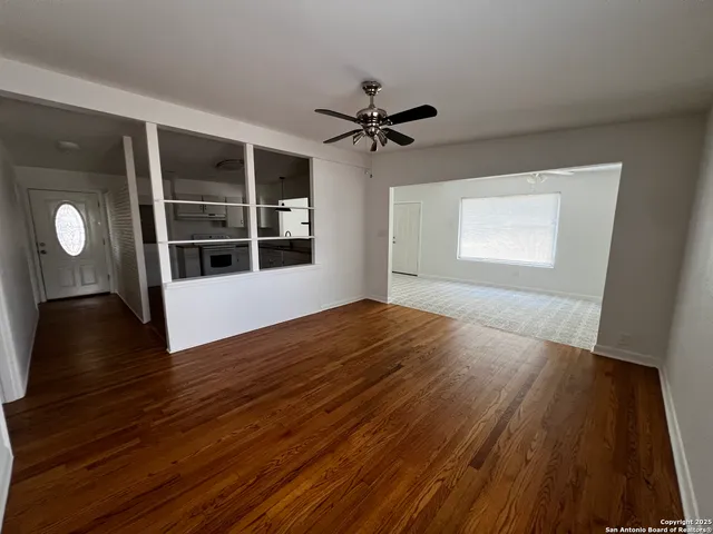 a view of empty room with wooden floor and fan