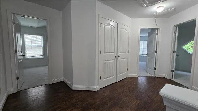 a view of an empty room with wooden floor and a bathroom