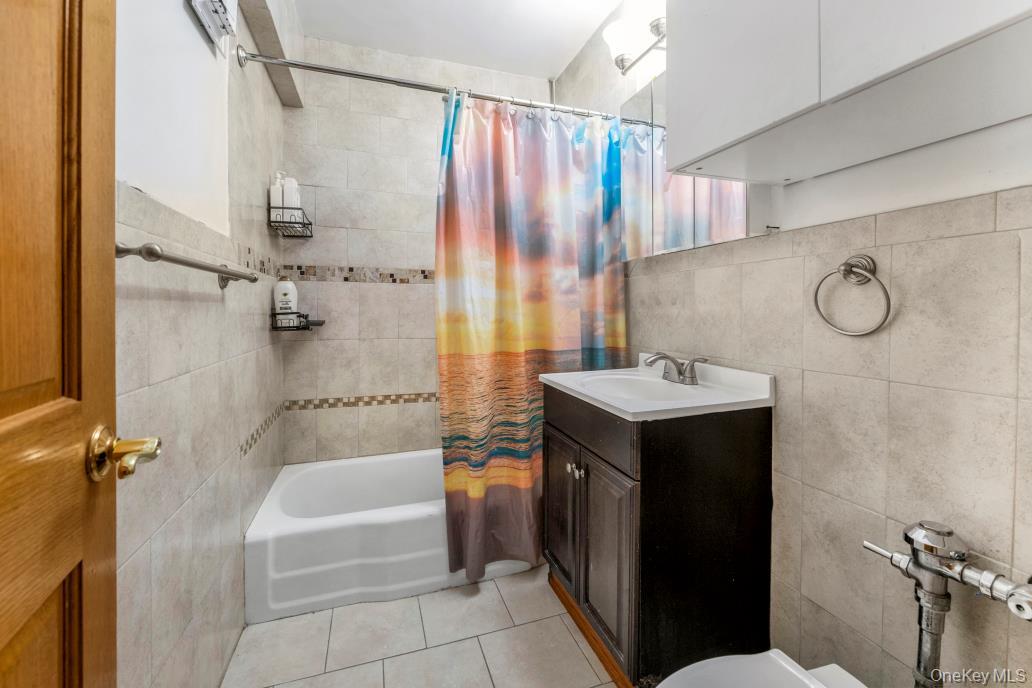 108-50 62nd Drive, Unit 3F Queens, NY 11375 - Photo 8 of 11 a bathroom with a sink vanity mirror and a bathtub