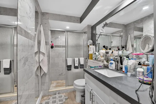 a bathroom with a granite countertop sink a toilet a mirror and shower