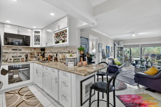 a kitchen with stainless steel appliances granite countertop a stove a sink a dining table and chairs