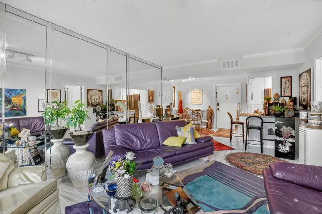 a living room with furniture potted plant and kitchen view