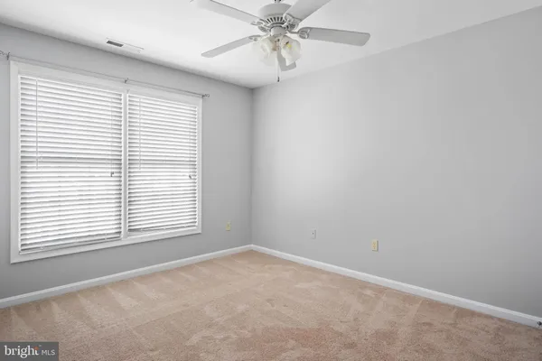 an empty room with a window and a fan