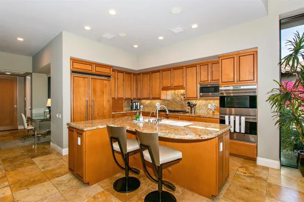 a kitchen with stainless steel appliances kitchen island granite countertop a sink counter space and a view of living room