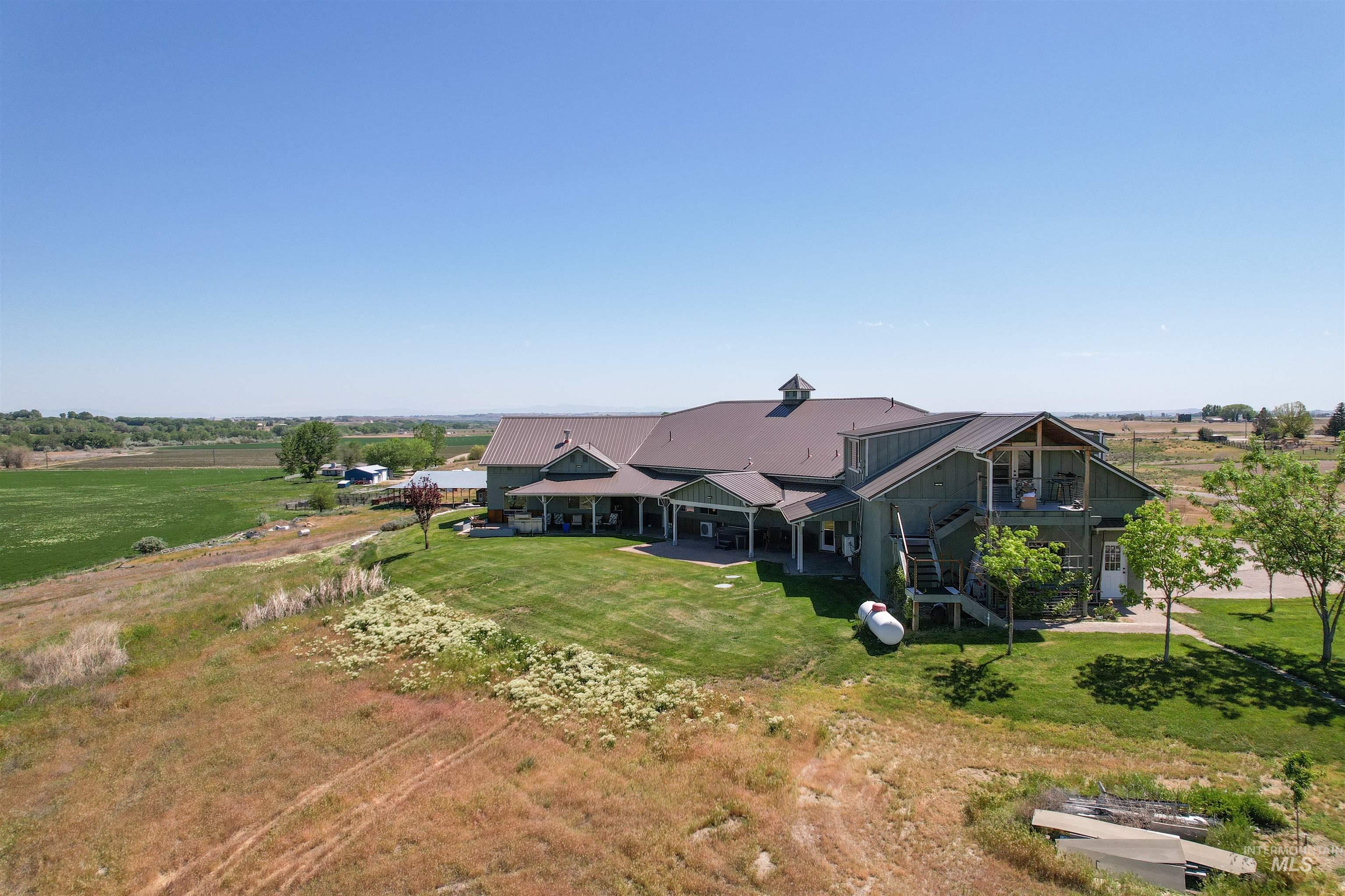 1030 Desert Glen Road Adrian, OR 97901 - Photo 10 of 47 Expansive property featuring a large residence with a metal roof, a full-length covered porch, and a two-story exterior balcony