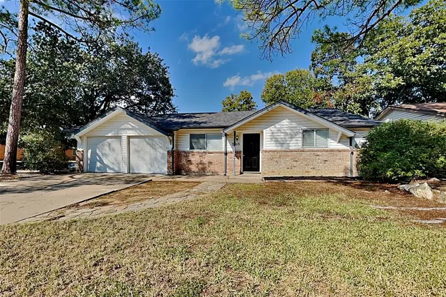 a view of a house with a yard and large tree