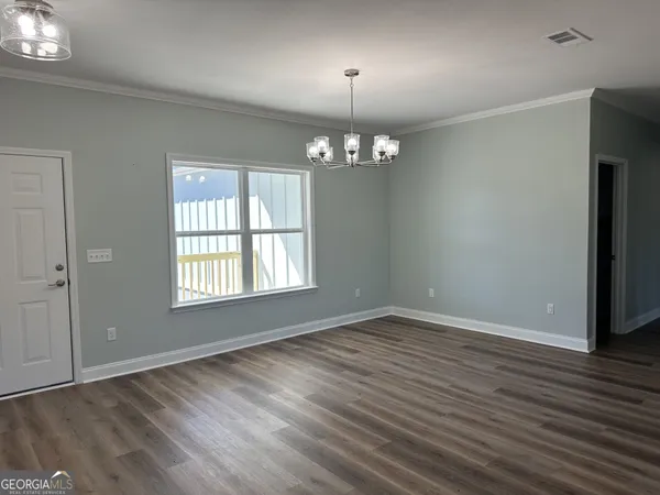 an empty room with wooden floor chandelier and windows