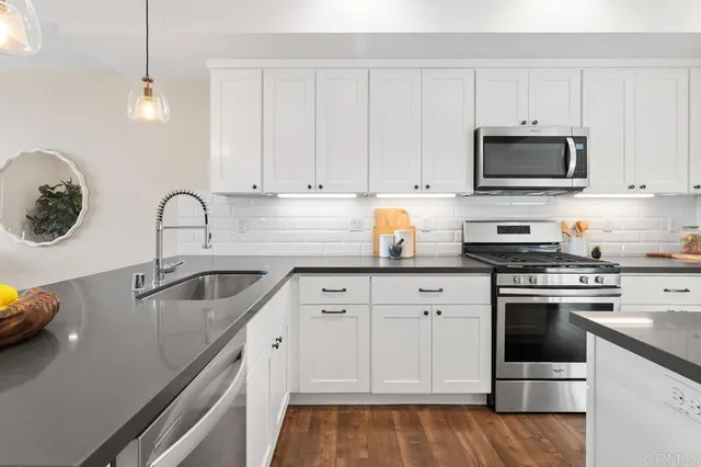 a kitchen with granite countertop a sink stainless steel appliances and cabinets