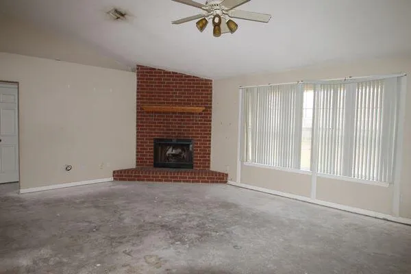 a view of an empty room with a fireplace and a window