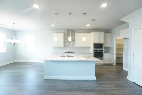 a kitchen with stainless steel appliances kitchen island granite countertop a stove a sink and a refrigerator