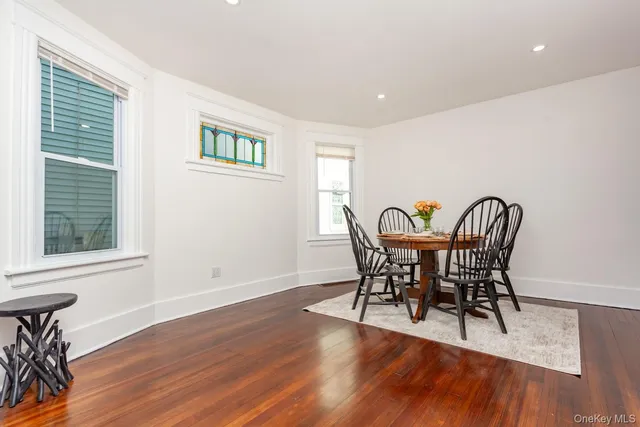 a view of a dining room with furniture a potted plant and wooden floor
