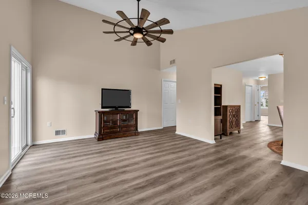 a view of a livingroom with a flat screen tv wooden floor and a ceiling fan