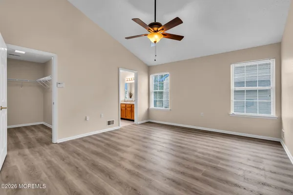 an empty room with wooden floor fan and windows