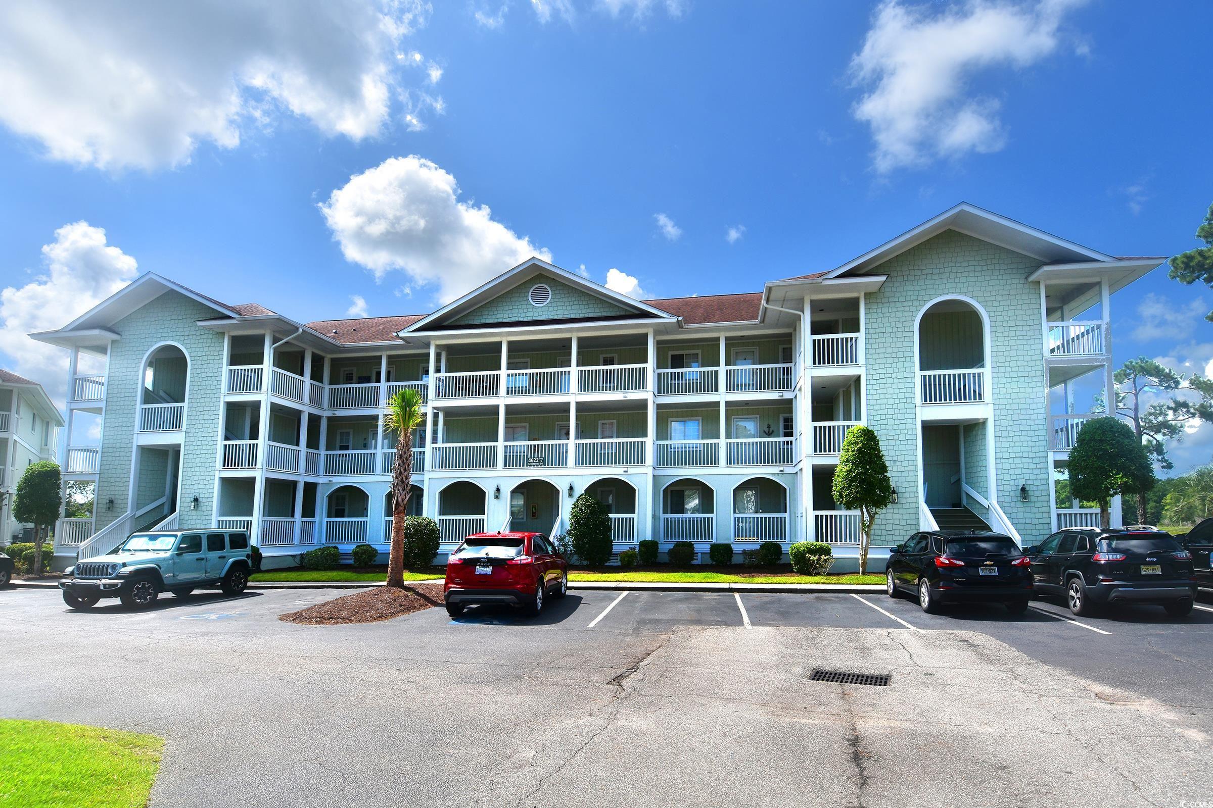 View of apartment building / complex with uncovered parking