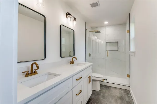 a bathroom with a double vanity sink double mirror and a toilet
