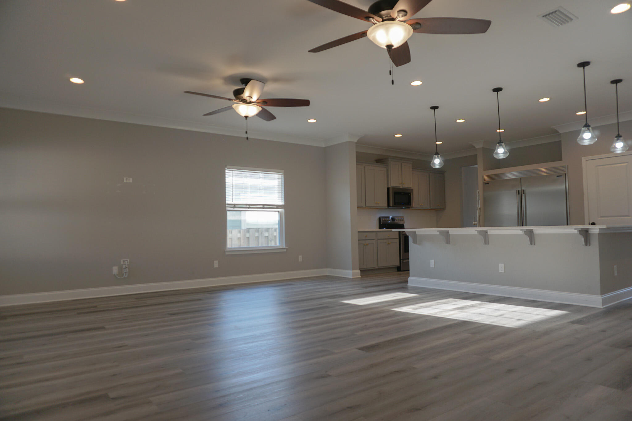 48 9th Avenue Shalimar, FL 32579 - Photo 18 of 60 an empty room with wooden floor a ceiling fan and kitchen space