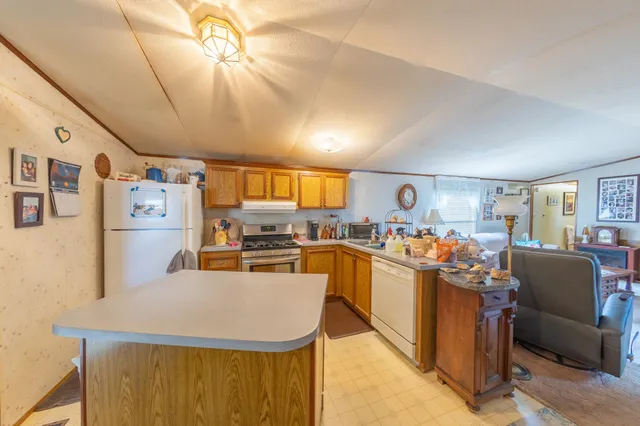 a view of a kitchen with kitchen island a large counter top space a sink a window and stainless steel appliances
