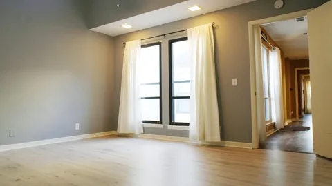 an empty room with wooden floor fan and windows