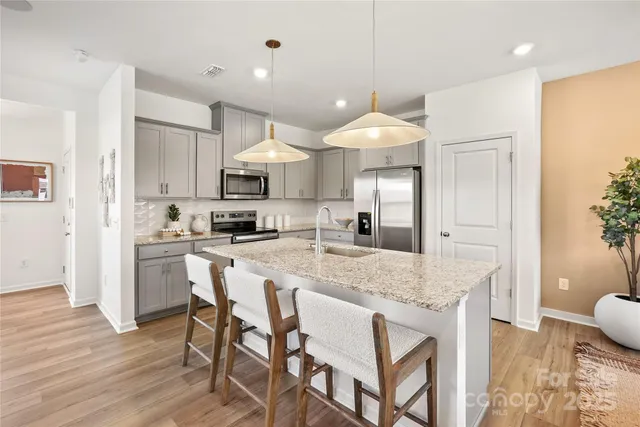 a kitchen with kitchen island granite countertop a sink cabinets and wooden floor