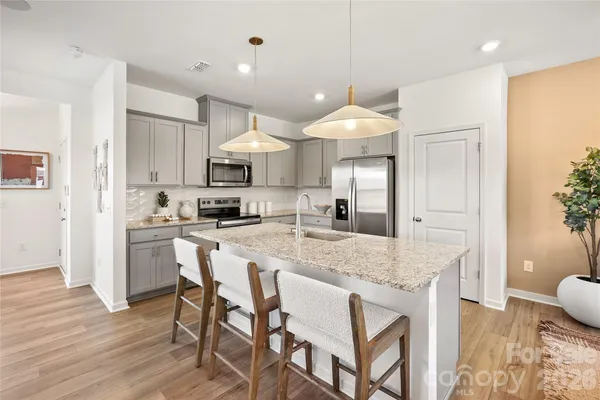 a kitchen with kitchen island granite countertop a sink cabinets and wooden floor