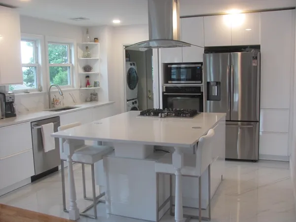 a kitchen with stainless steel appliances a kitchen island hardwood floor and a sink