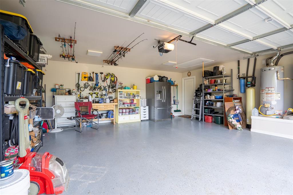 1920 Meander Road Granbury, TX 76049 - Photo 37 of 40 Spacious garage featuring a durable epoxy floor coating, painted walls, overhead storage racks, and an accessible attic hatch