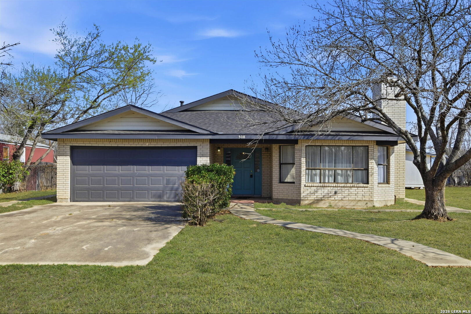 508 Crouch Avenue Devine, TX 78016 - Photo 1 of 26 a front view of a house with a garden and trees