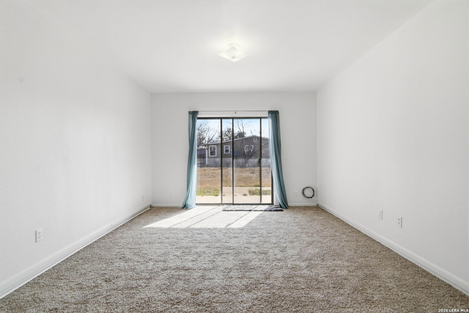 508 Crouch Avenue Devine, TX 78016 - Photo 11 of 26 an empty room with large windows and a fireplace