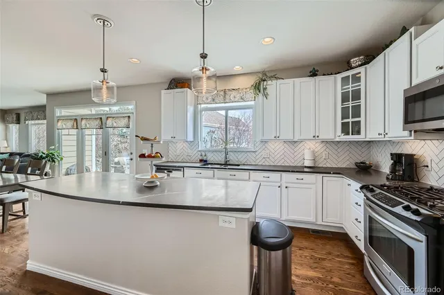 a kitchen with kitchen island granite countertop a sink cabinets and stainless steel appliances
