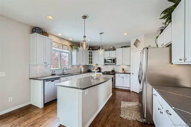 a kitchen with stainless steel appliances granite countertop a sink a stove a refrigerator and island