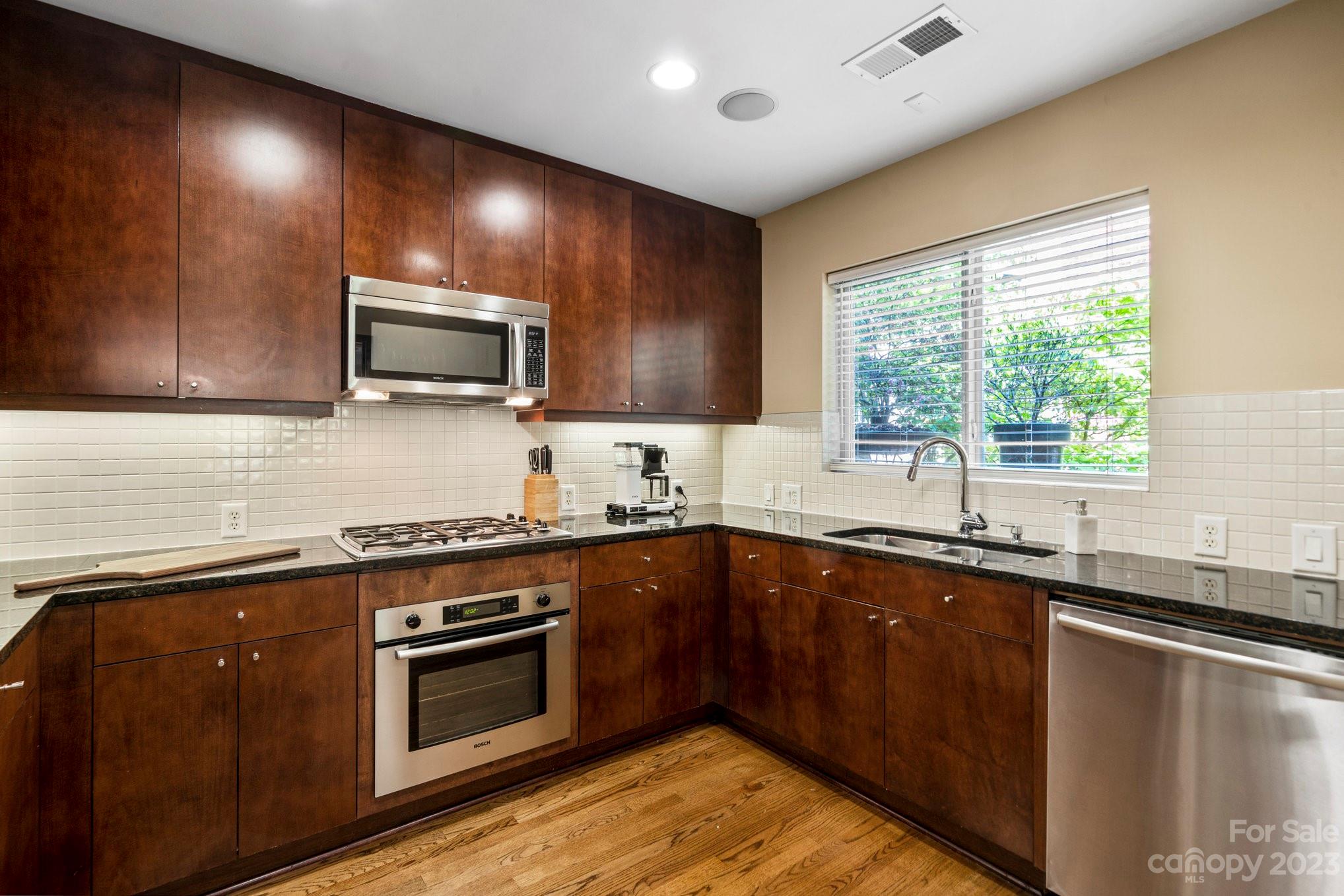 420 Queens Road, Unit 3 Charlotte, NC 28207 - Photo 7 of 35 a kitchen with stainless steel appliances wooden cabinets a sink and a stove