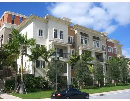 a view of a white building among the street with palm trees
