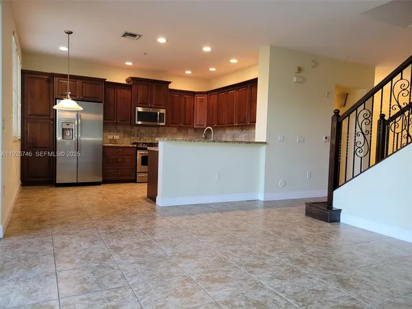 a view of kitchen with stainless steel appliances granite countertop a refrigerator and a stove top oven