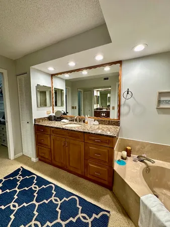 a spacious bathroom with a tub sink and mirror