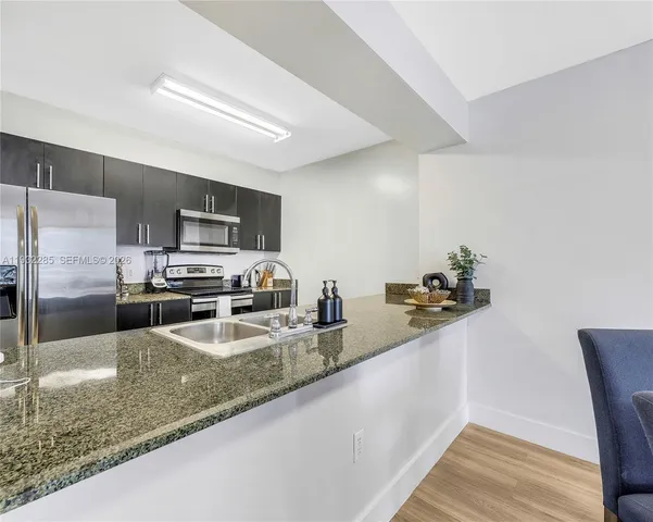 a kitchen with stainless steel appliances granite countertop a sink a stove top oven a counter space and cabinets