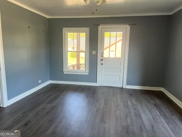 an empty room with wooden floor and windows