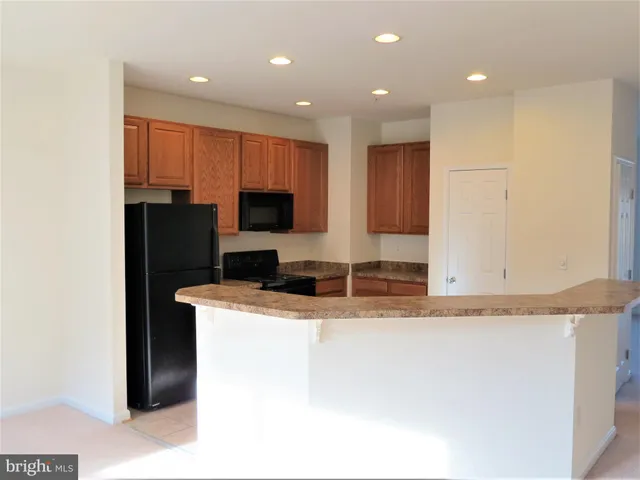 a kitchen with kitchen island granite countertop a sink a refrigerator and a stove